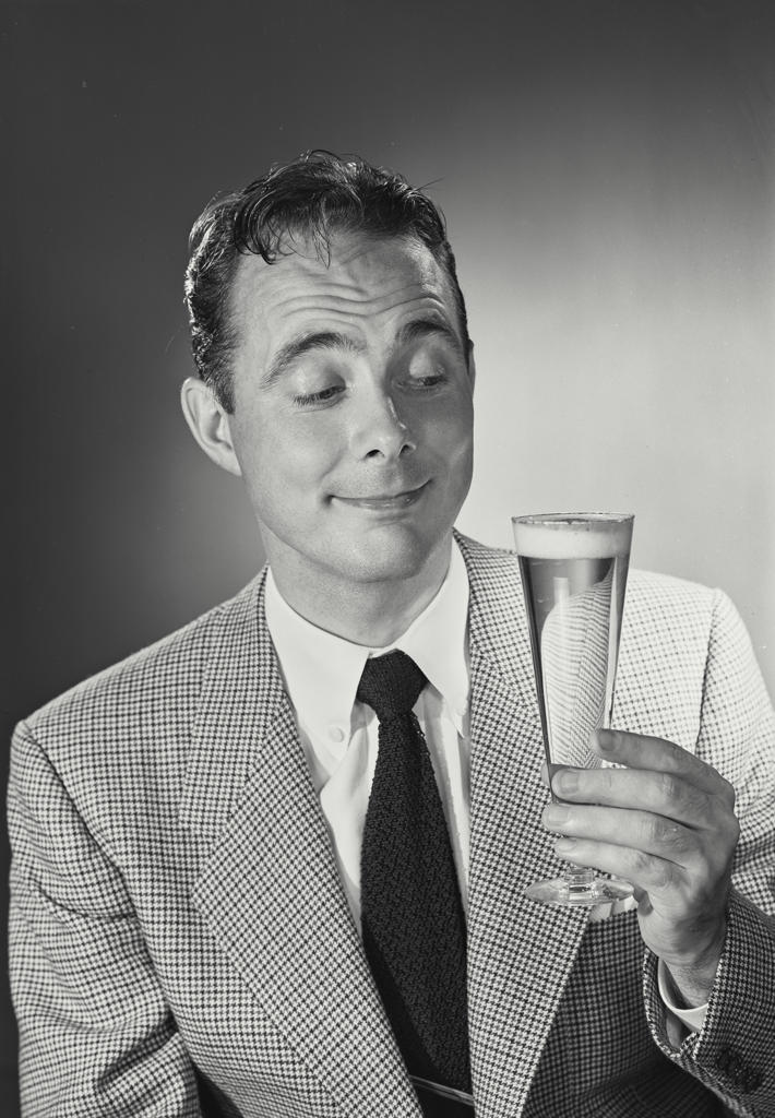 Portrait of man in suit and tie smiling holding glass