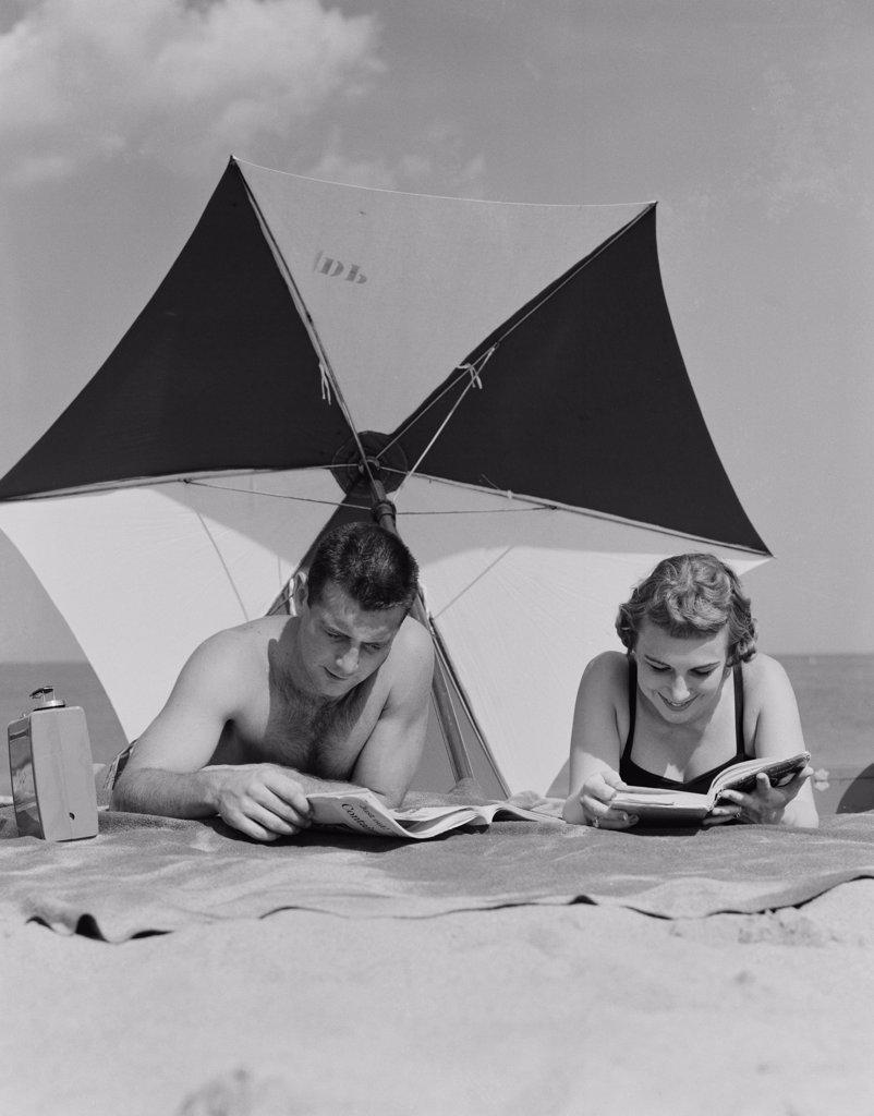 Young couple reading books on beach
