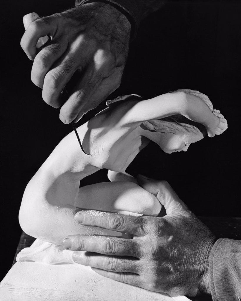 Close-up of a person's hands carving a statue