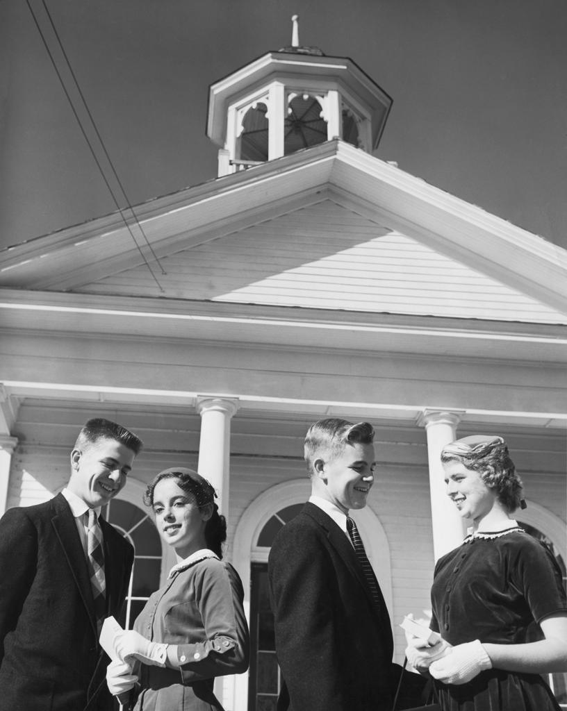 Two young couples standing in front of church