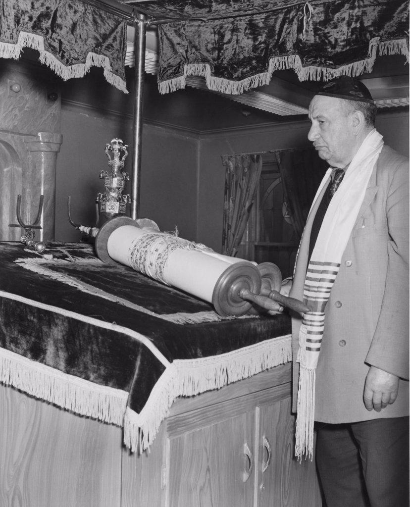 Side profile of a rabbi standing near the Torah