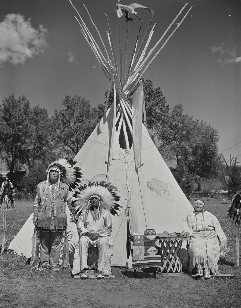 Two senior men and a senior woman outside a teepee