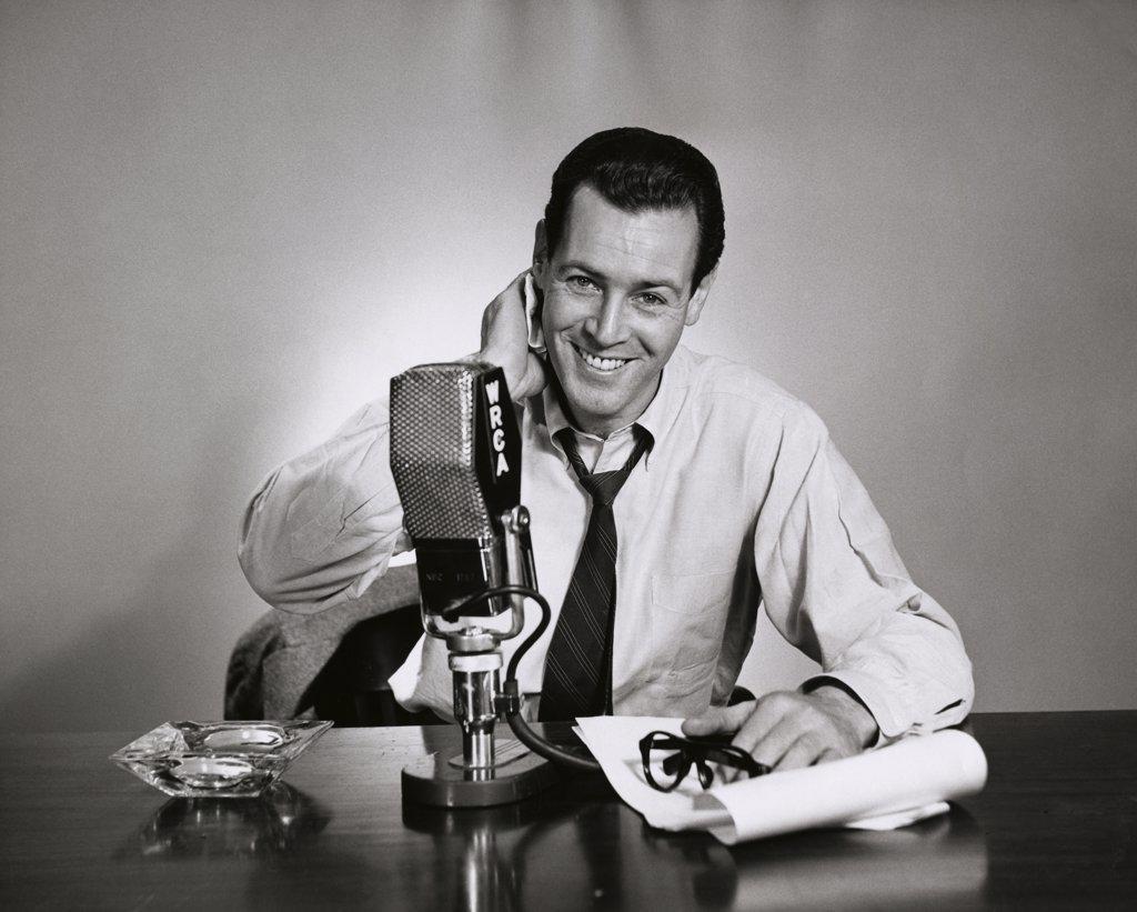 Portrait of a mid adult man sitting in front of a microphone in a radio station