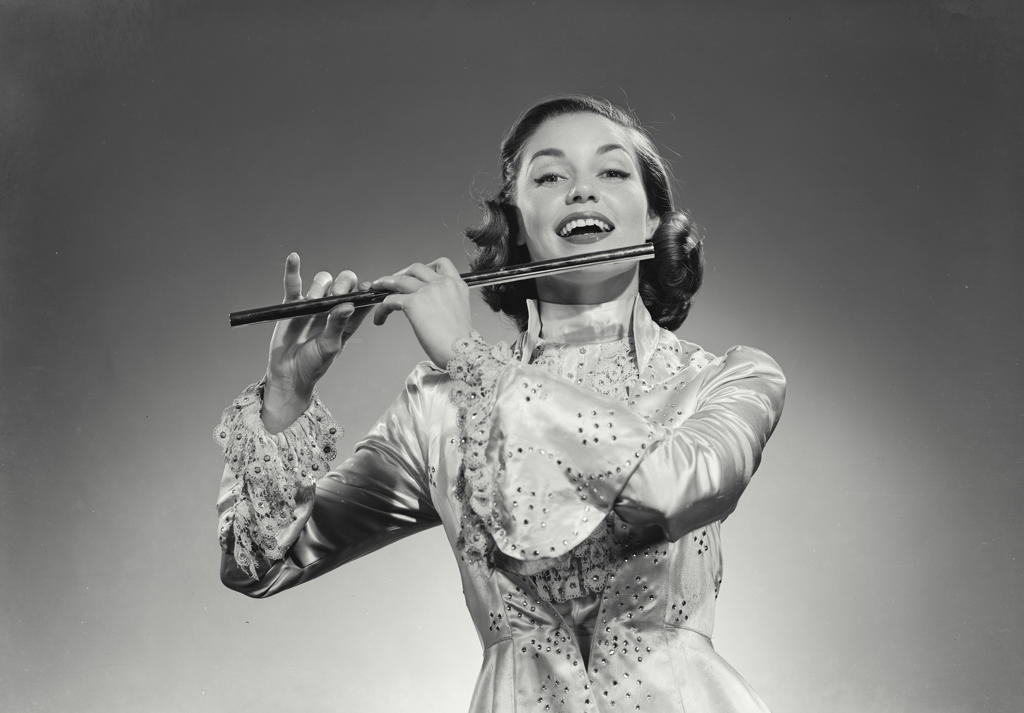 Young woman playing a flute and smiling
