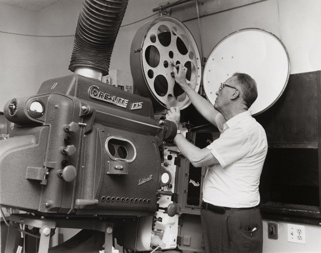 Side profile of a mature man operating a film projector