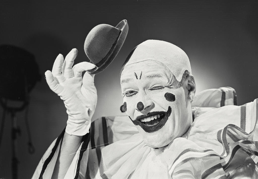 Portrait of clown putting on silly hat.