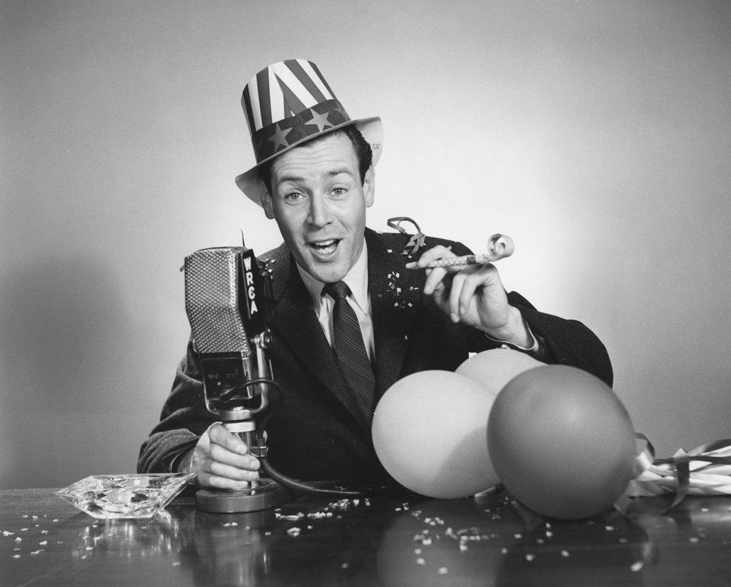 Studio portrait of man with microphone and party blower