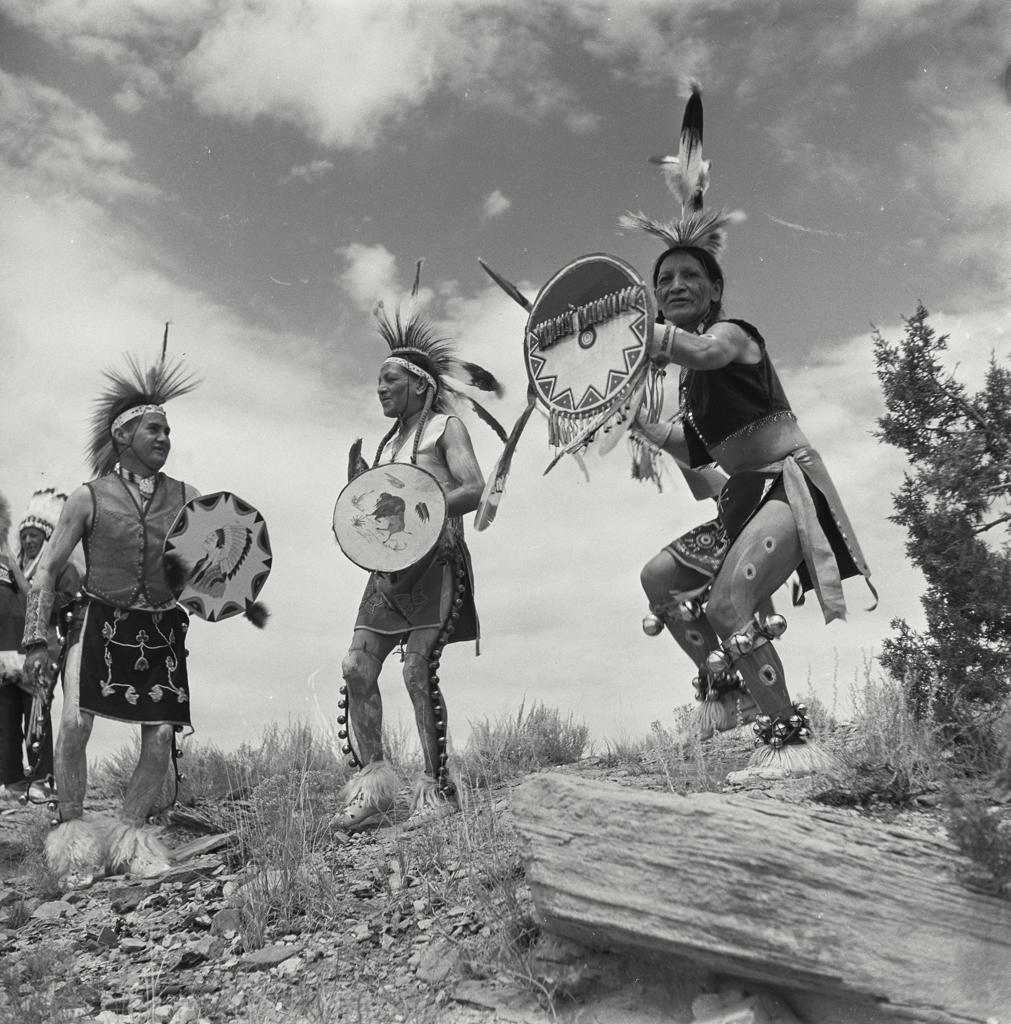 Four tribal men standing and holding shields