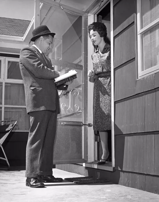 Young woman standing in a doorway and talking to a door to door salesman