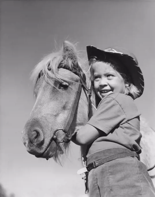Low angle view of a girl standing with a horse and smiling
