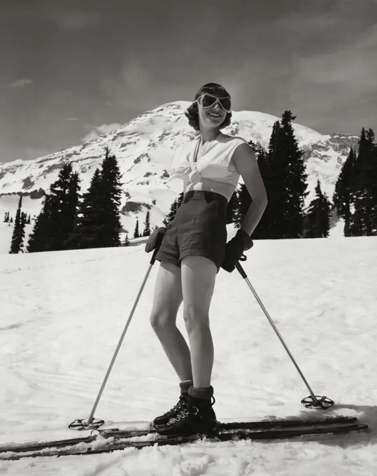 Young woman standing with skiing equipment and smiling