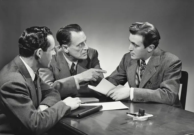 Vintage Photograph. Group of businessmen sitting at desk talking