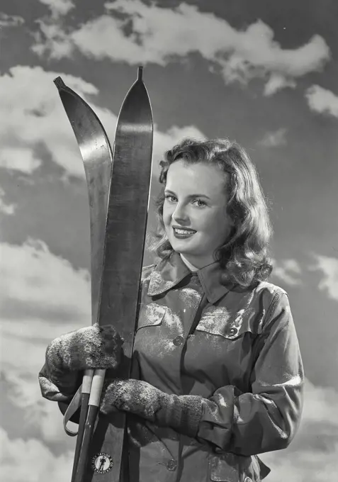 Portrait of a young woman holding skis