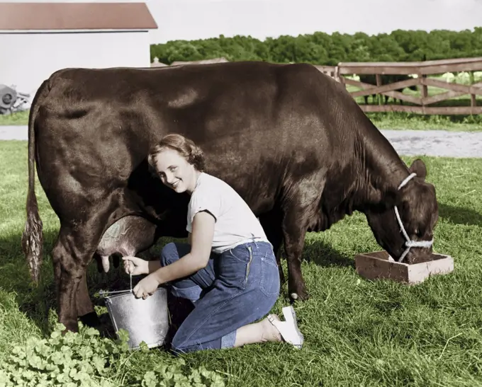 Portrait of a young woman milking a cow