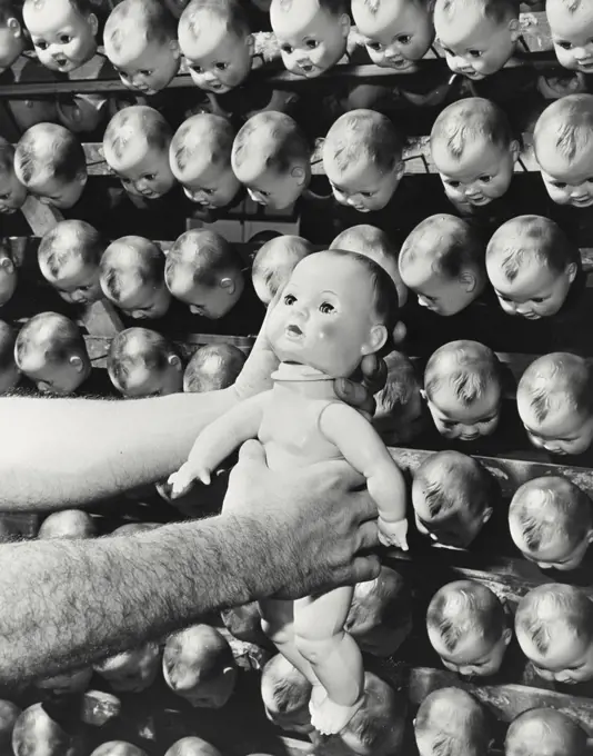 Vintage photograph. Doll manufacturing - placing head of doll on body