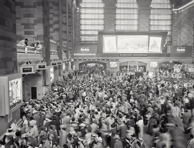 Vintage photograph. View looking at Kodak Exhibit sign behind crowd of people at a busy Grand Central Station.
