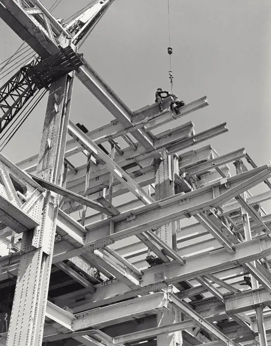 Vintage photograph. View looking up at men sitting on steel girders on a construction site near the United Nations Building, New York City