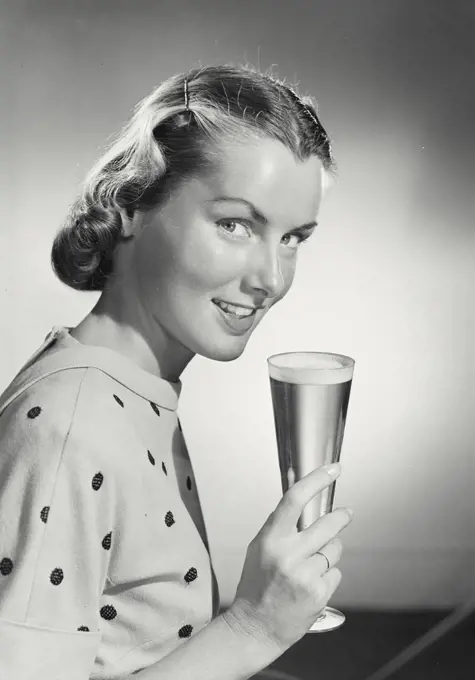 Vintage photograph. Woman holding glass and smiling.