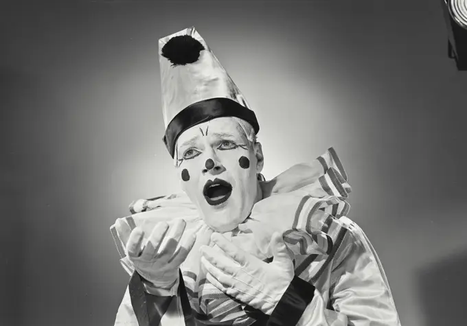 Vintage photograph. Portrait of clown in silly hat with mouth open.