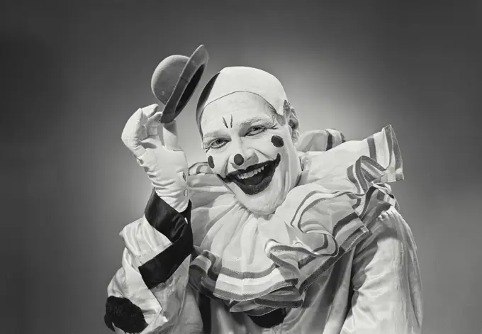 Vintage photograph. Portrait of clown putting on silly hat.