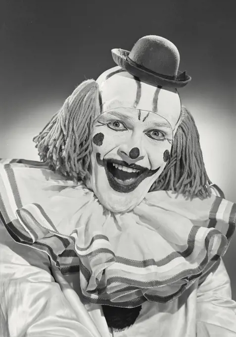 Vintage photograph. Portrait of clown wearing silly hat and smiling wide.