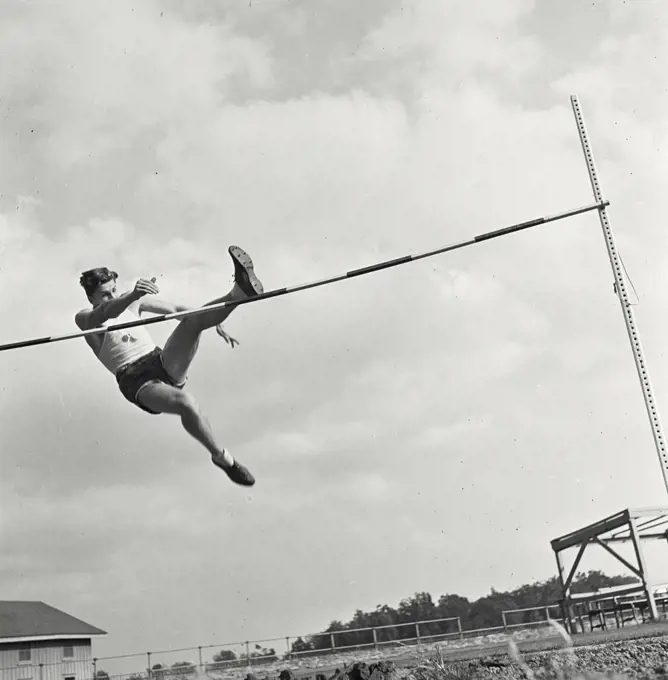 Vintage photograph. High bar jump athlete mid jump