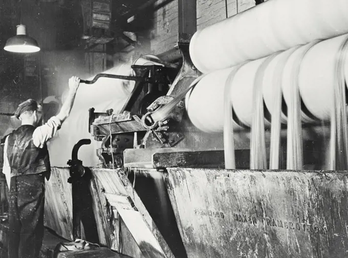 Vintage photograph. At a British cotton factory, the printed cloth has to be finally cleaned and shrunk and this is done by passing it in a continuous band through hot water and numerous rollers.