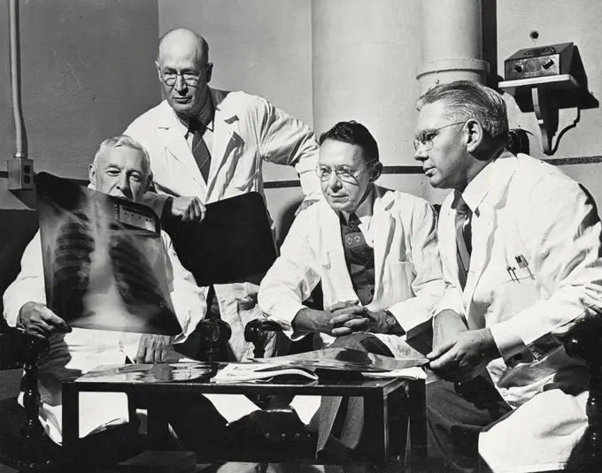 Vintage photograph. Four doctors examining an X-Ray of a chest