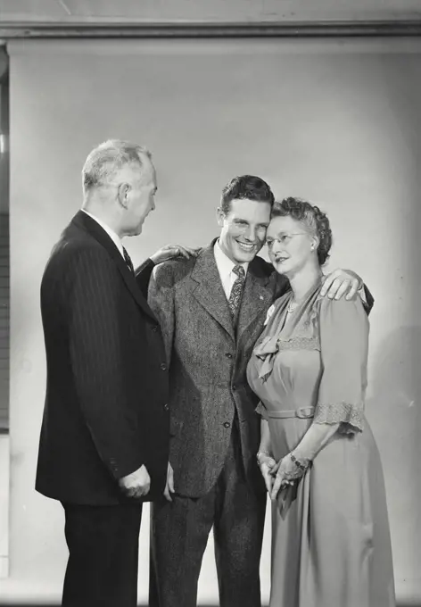 Vintage photograph. Young man standing with mother and father smiling