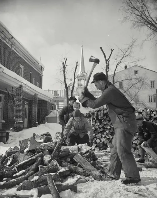 Vintage photograph. Men chopping firewood in snow with church in distance