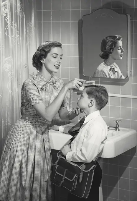 Mother combing young boys hair in bathroom