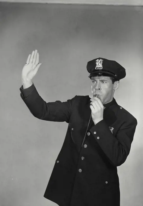 Vintage photograph. Man in police uniform blowing whistle