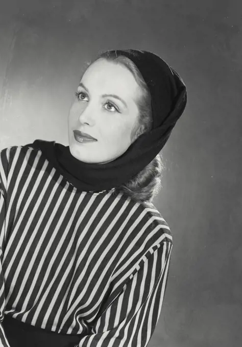 Vintage photograph. Blonde woman wearing striped blouse head scarf looking up at corner