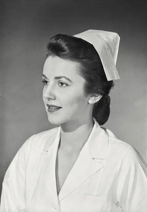 Vintage photograph. quarter profile view of brunette woman wearing nurse's uniform