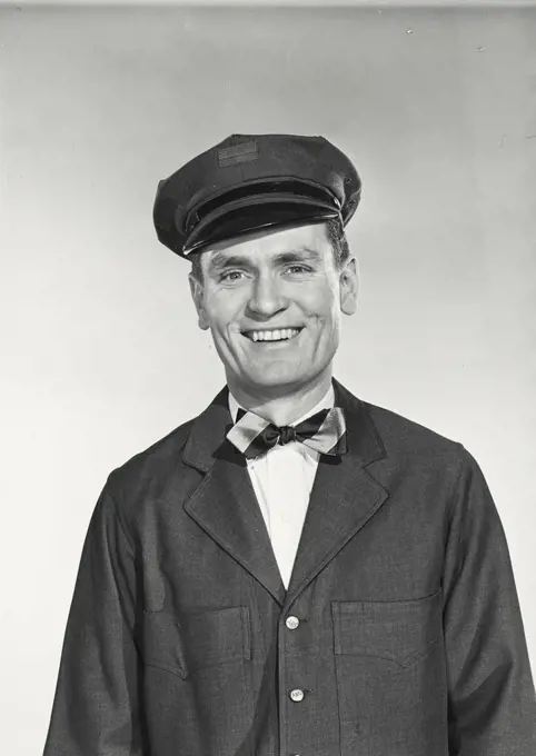 Vintage photograph. Mailman in uniform with hat and bow tie smiling