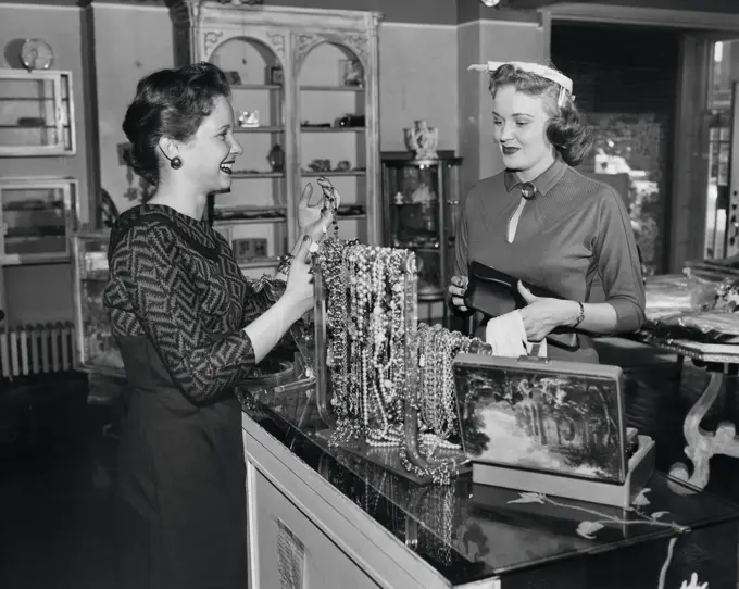 Side profile of a female sales clerk showing jewelry to a customer
