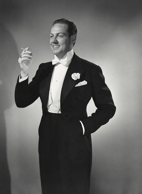 Vintage photograph. Man in tuxedo holding up cigarette