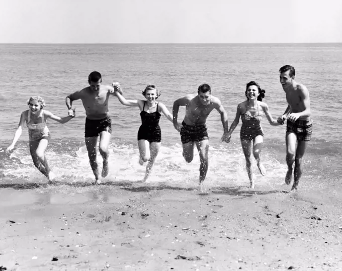 Three young couples running on beach