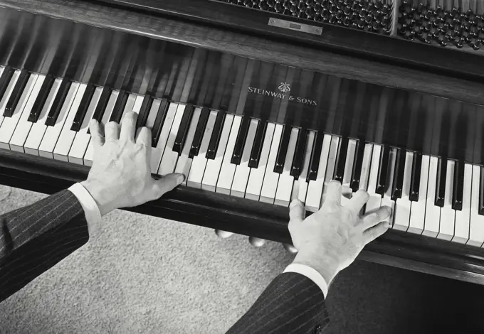 High angle view of a man's hands playing the piano
