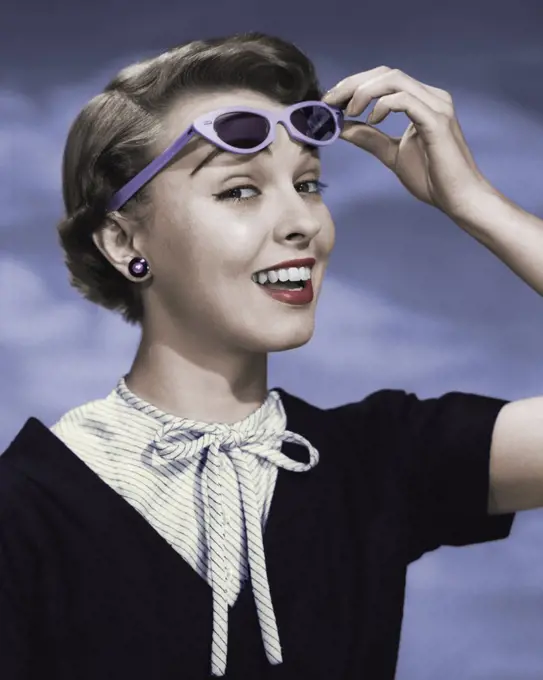 Close-up of young woman holding sunglasses