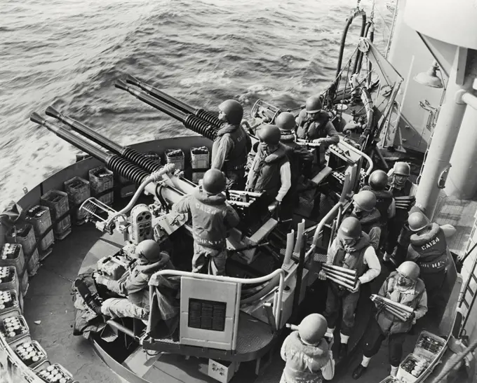 Vintage photograph. 40 mm gun crew standing an alert watch aboard the USS Rochester (CA-124) during operations in the Formosa area