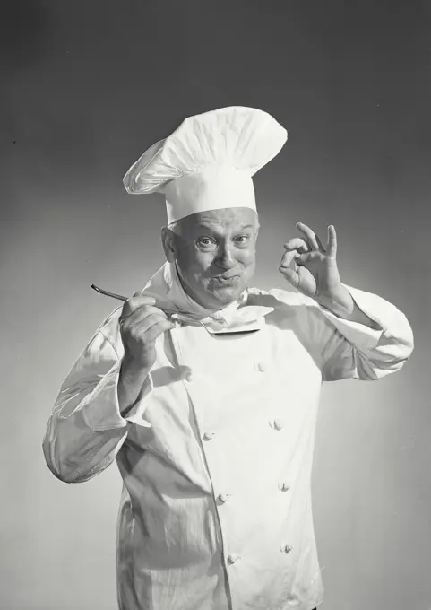 Vintage photograph. Man in chef uniform tasting spoon