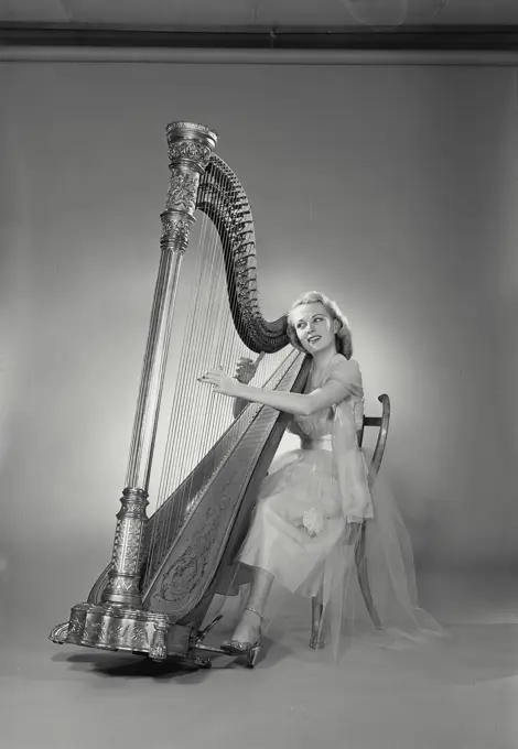 Vintage Photograph. Woman in dress sitting in chair playing Grand Pedal Harp. Frame 11