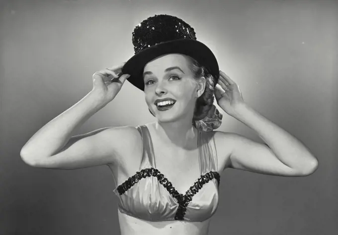 Vintage photograph. Young woman smiling in bra and top hat