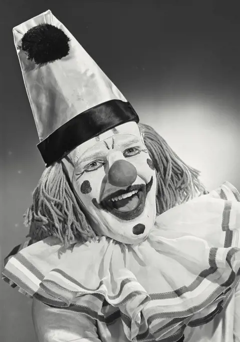 Vintage photograph. Portrait of clown wearing silly hat and smiling wide.