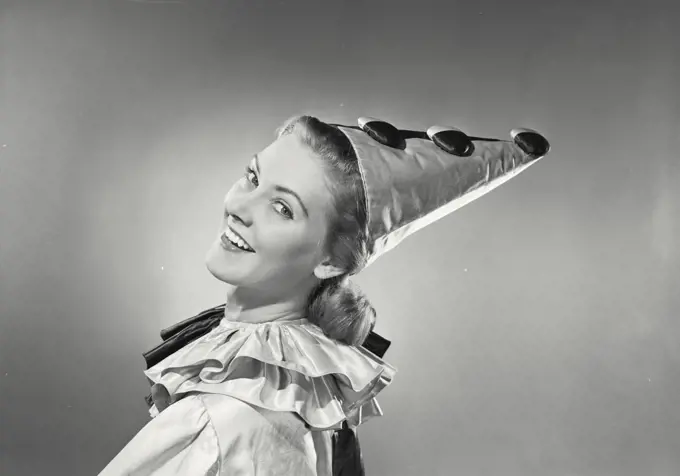 Vintage photograph. Portrait of a young woman in clown suit looking over shoulder and smiling.