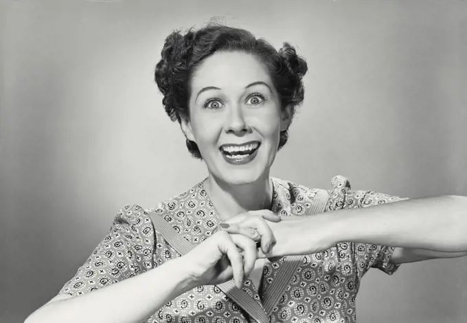 Vintage photograph. Brunette woman smiling with wide eyes holding hands up with fingers clasped