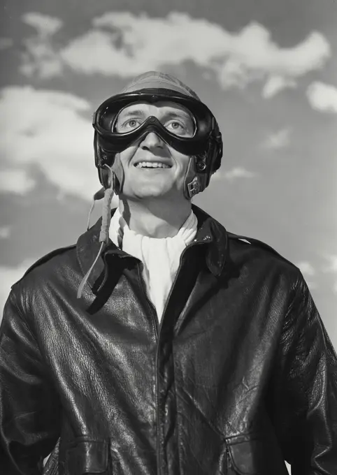 Vintage Photograph. Man in pilot gear and goggles with clouds in background