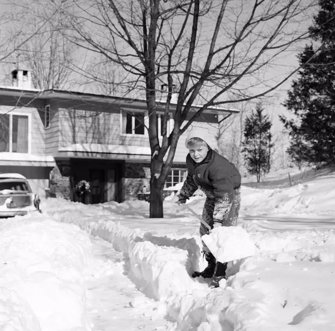Boy shoveling snow in front yard
