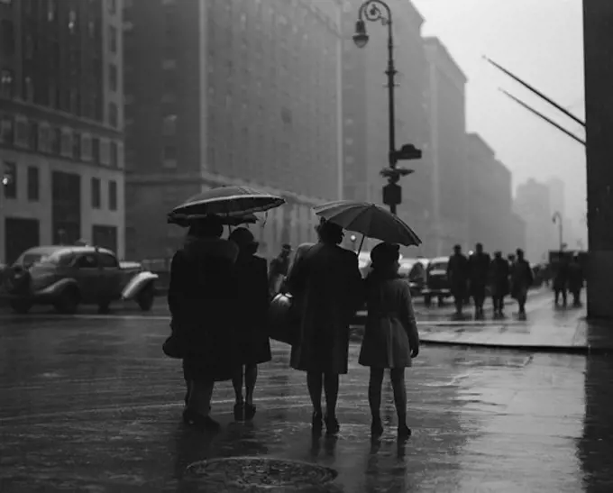 USA, New York State, New York City, People walking through street and holding umbrellas during rainy day